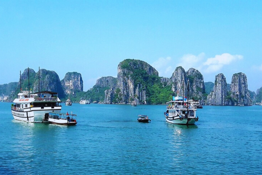 Two Halong Bay cruise boats sailing on clear blue water with Auasia Travel